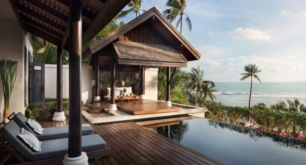 private outdoor patio with infinity pool palm tree and ocean in background