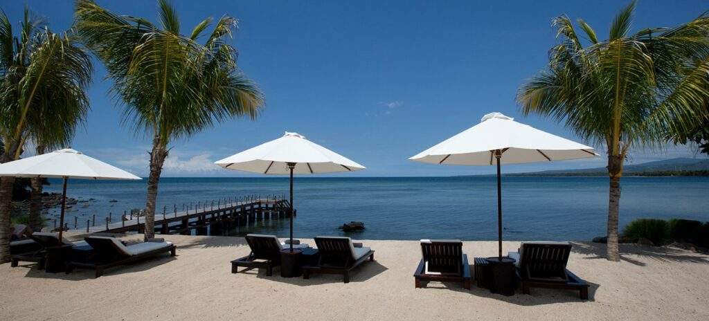 beach lounge chairs under white umbrellas on the beach