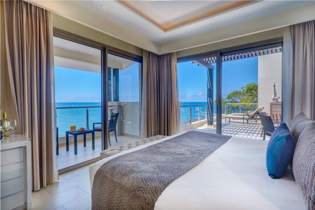 resort bed with wall to ceiling windows overlooking ocean