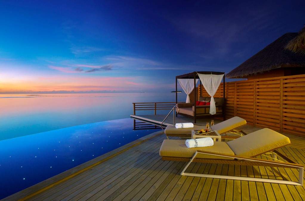 folding lawn chairs on deck facing water at sunset