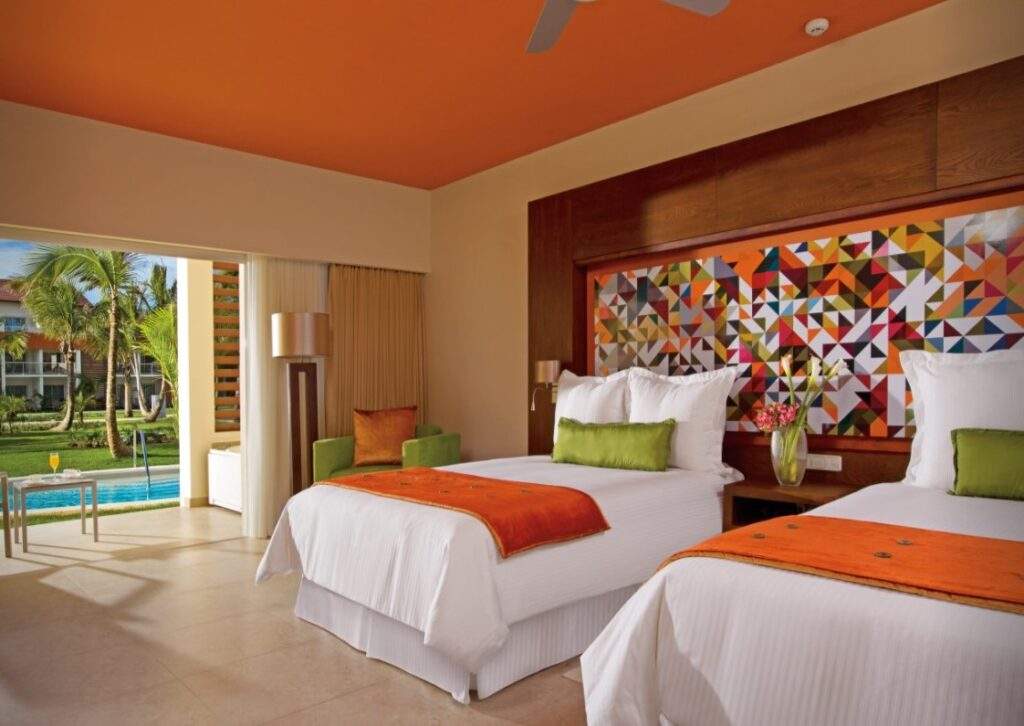bed with orange cover with floor to ceiling window