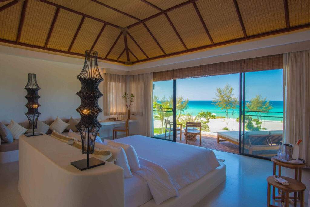 big wide bed facing open picture windows in front of ocean