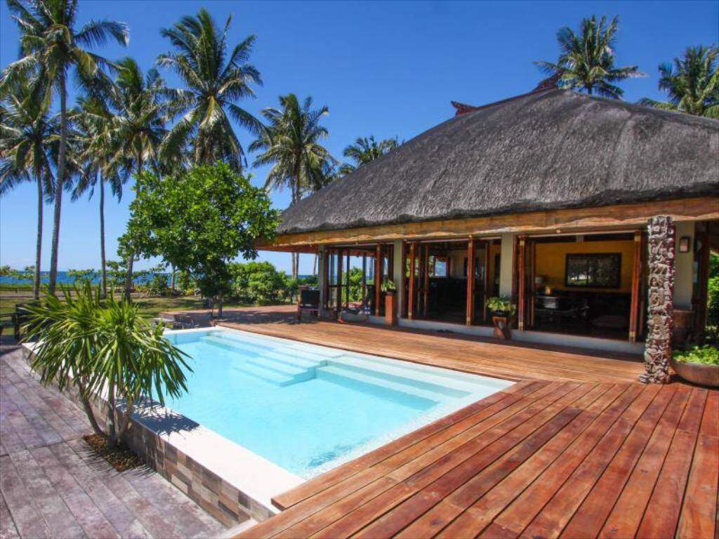 square pool with wood deck surrounded by palm trees