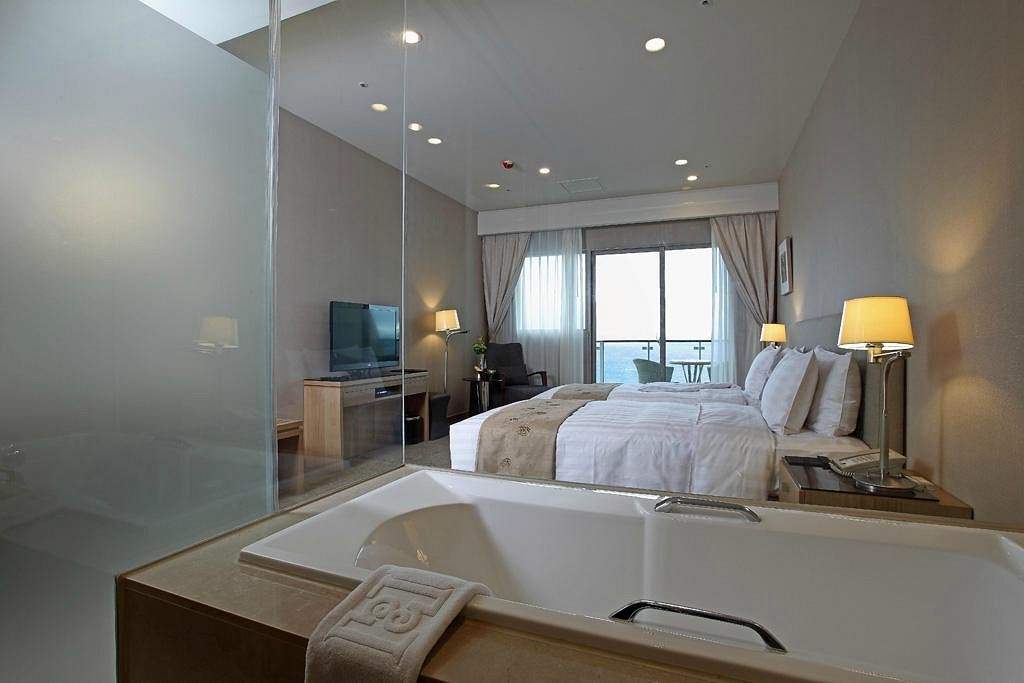 resort room with bathtub and large white bed