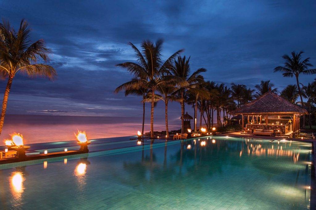 lighted pool with palm trees at beach at night