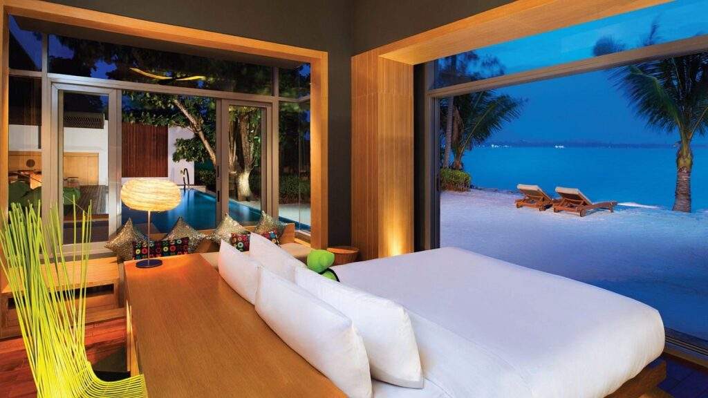 large bed in resort in front white sand beach
