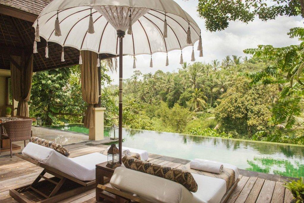 two lounge chairs under umbrella at pool