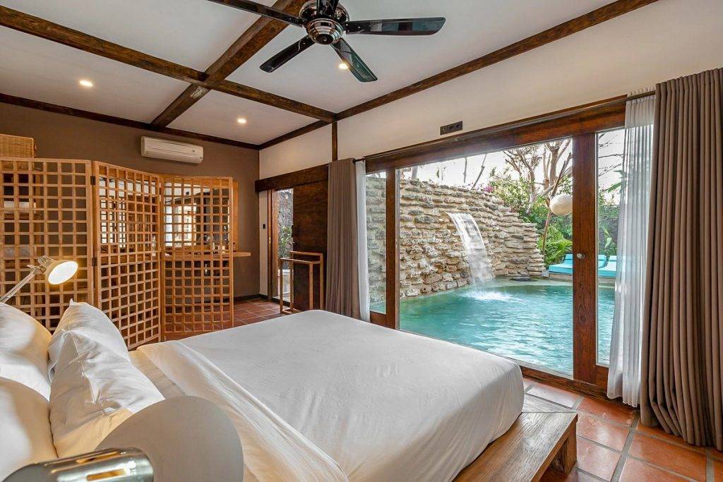 resort room with bed in front of private pool