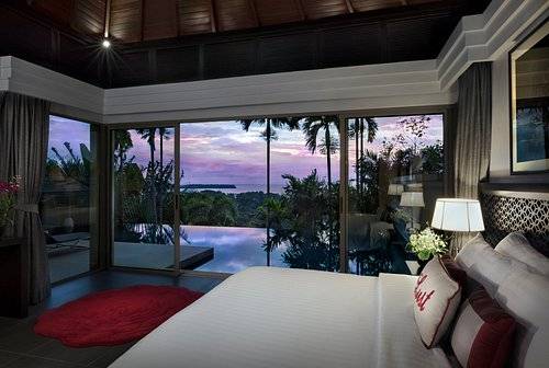 luxury resort room with wall-to-wall windows looking out on infinity pool