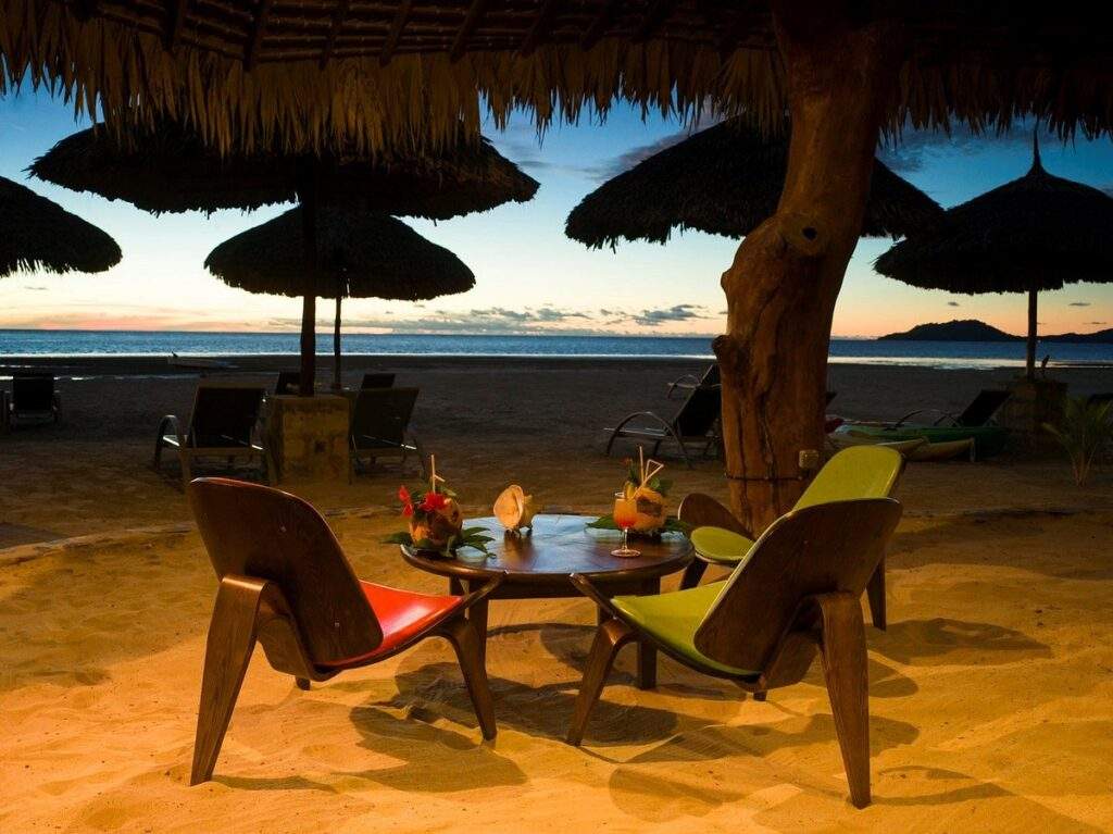 2 chairs with table in front of beach at sunset
