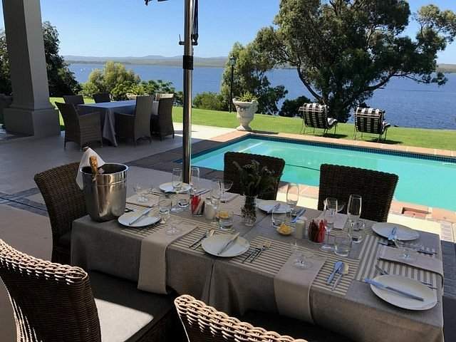 outdoor dinner table with pool behind