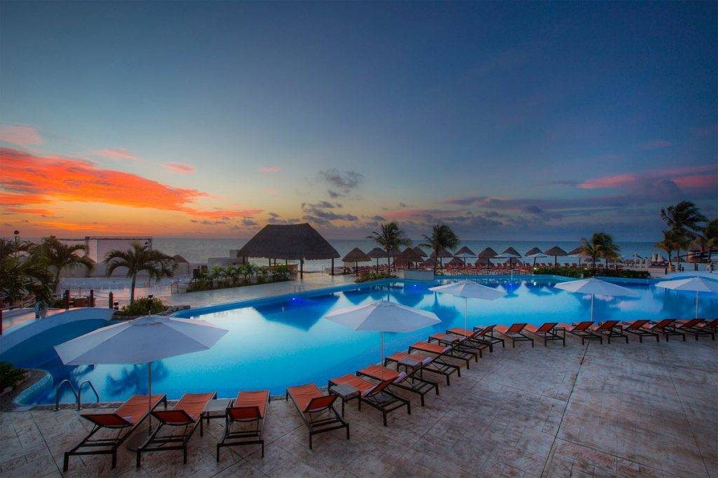 oval resort pool surrounded by chairs at sunset