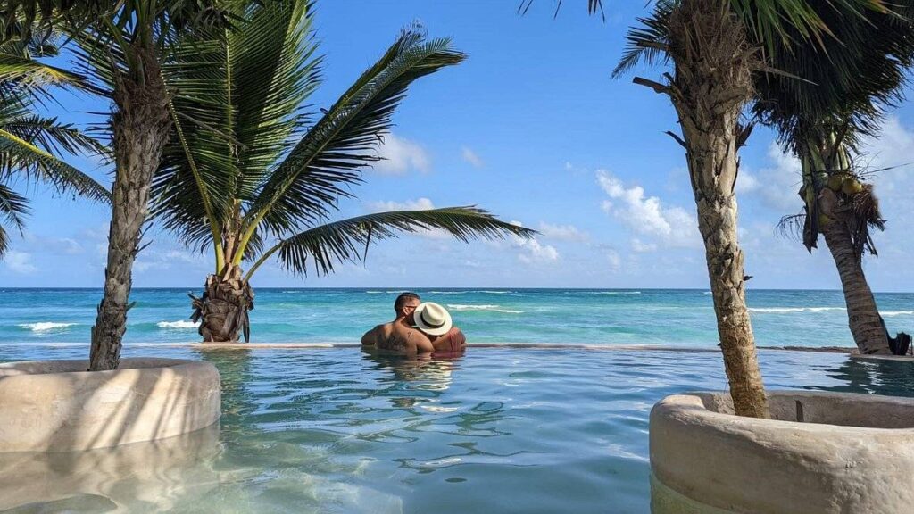 couple in infinity pool with palm trees