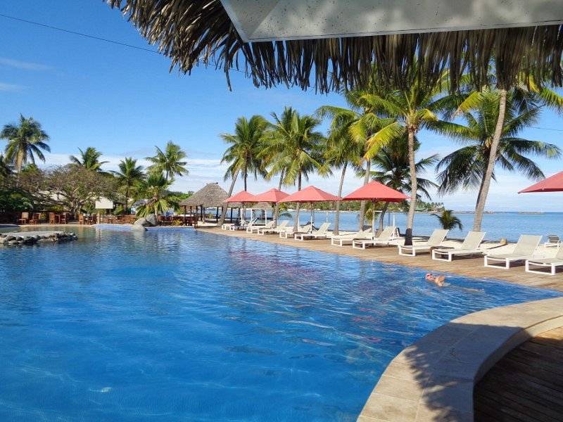large resort pool lined with umbrellas and lounge chairs
