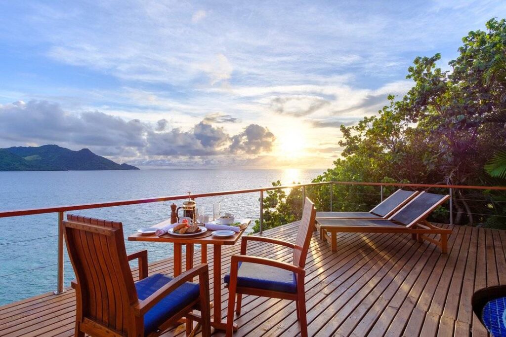 two chairs around table on deck looking at water at sunset
