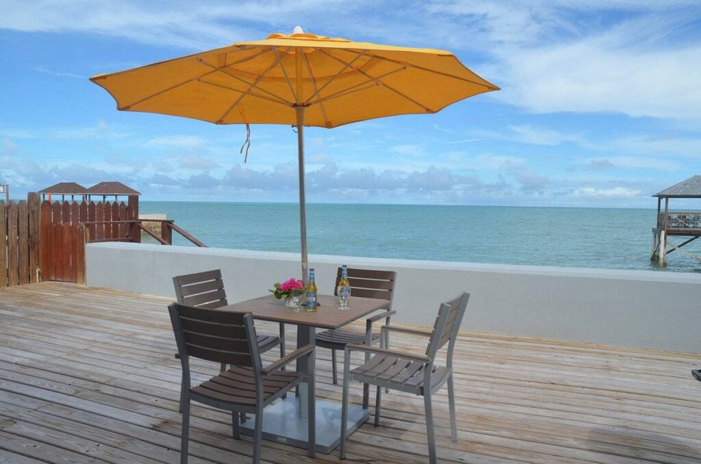 table with 4 chairs and umbrella on a beach
