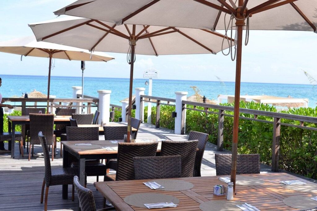 dining tables with umbrellas overlooking ocean