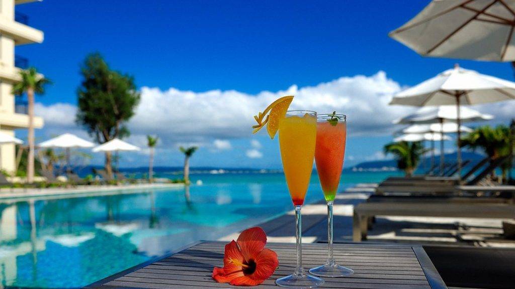 2 tropical drinks next to long resort infinity pool