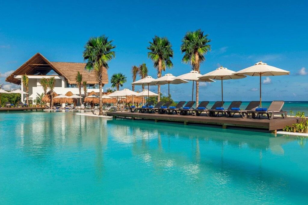 resort pool at the ocean with lounge chairs and umbrellas