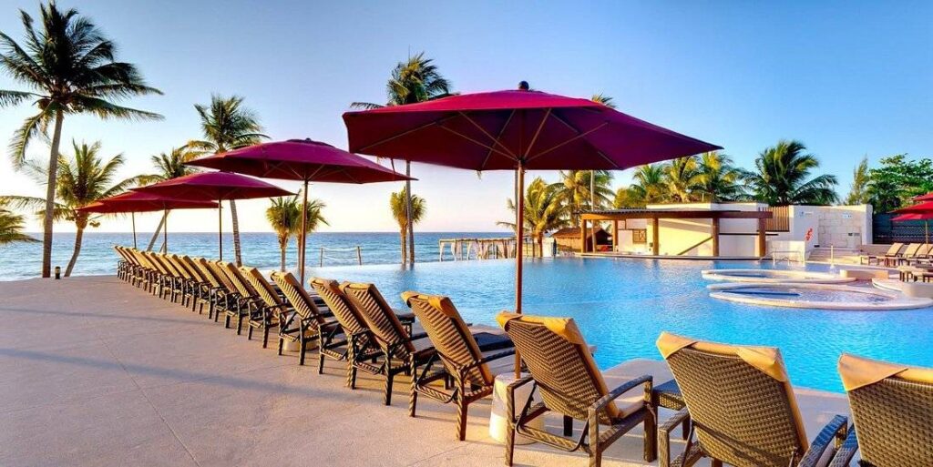 resort pool at the ocean with red umbrellas