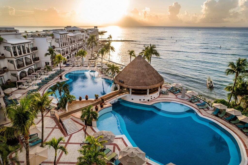 aerial view of resort pool next to ocean at sunset