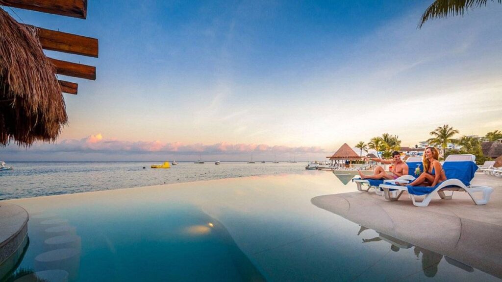 couple sitting next to infinity pool at ocean