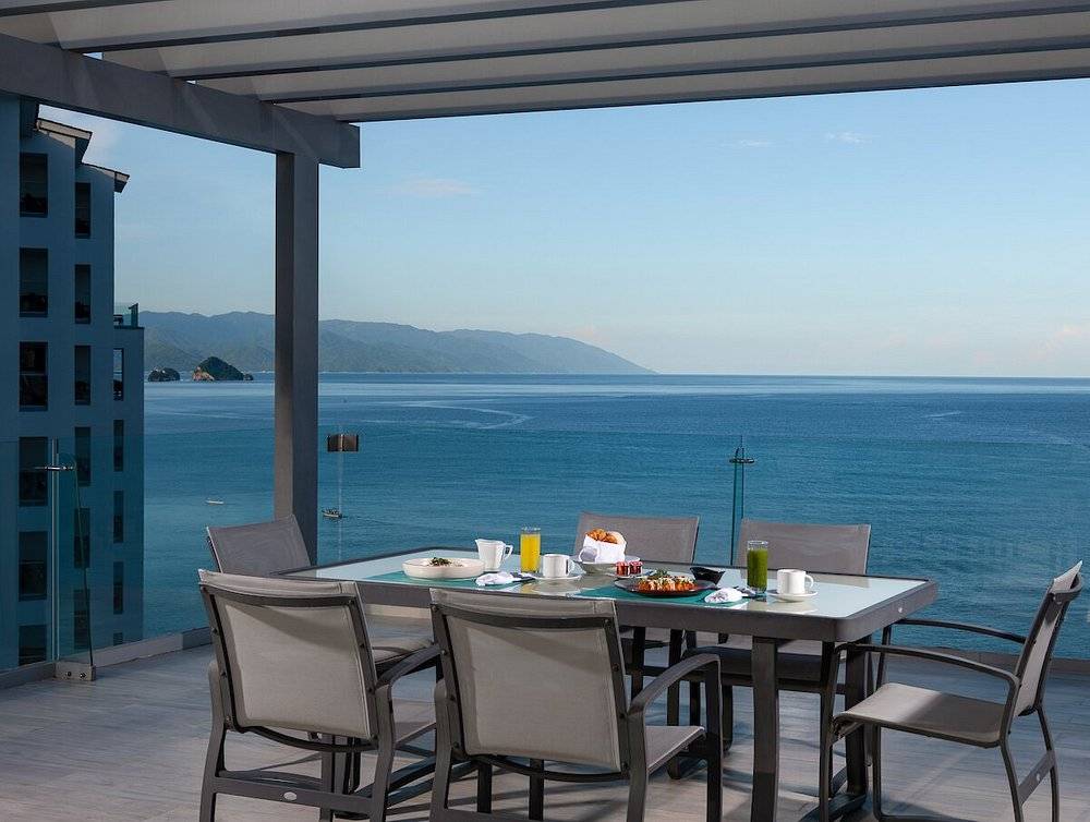 4 chairs around table under covering at ocean