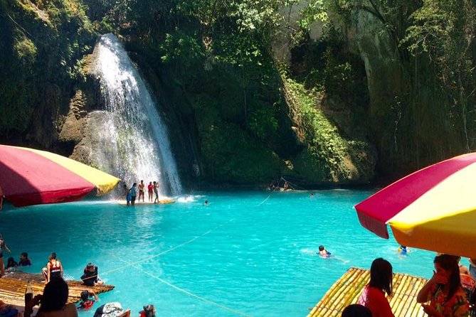 people swimming in lake with waterfall