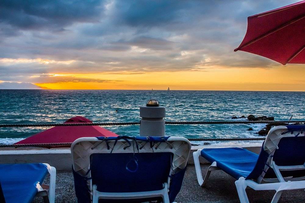 lounge chairs with red umbrellas on beach at sunset
