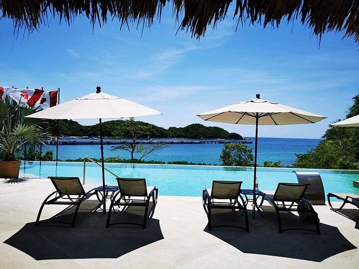 two umbrellas with lounge chairs in front of pool at beach