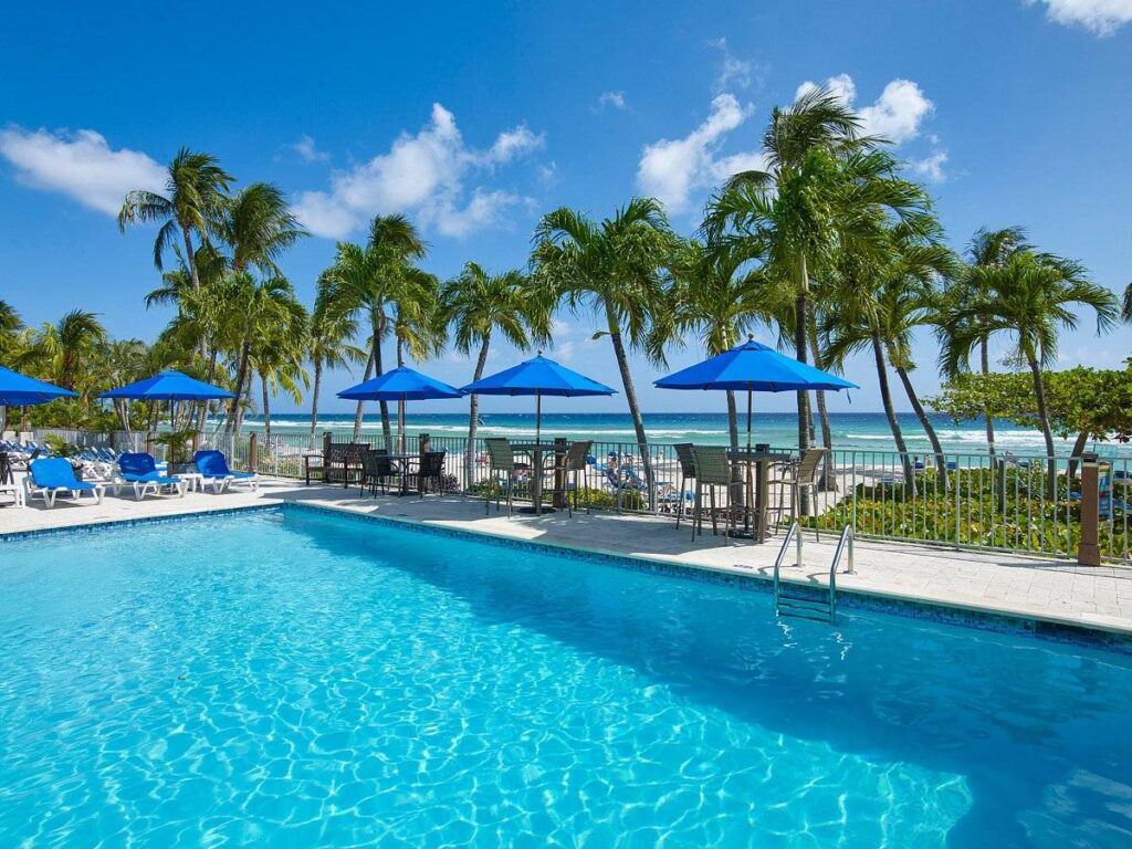 resort pool with lounge chairs blue umbrellas and palm trees