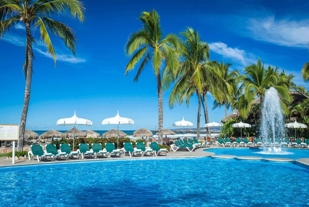 fountain in tropical resort pool with lounge chairs and umbrellas