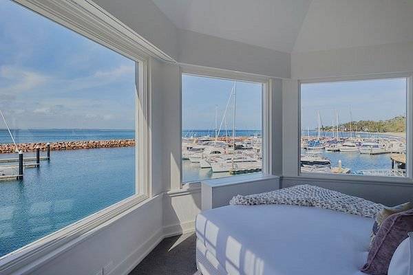 bed with 3 windows looking out onto ocean