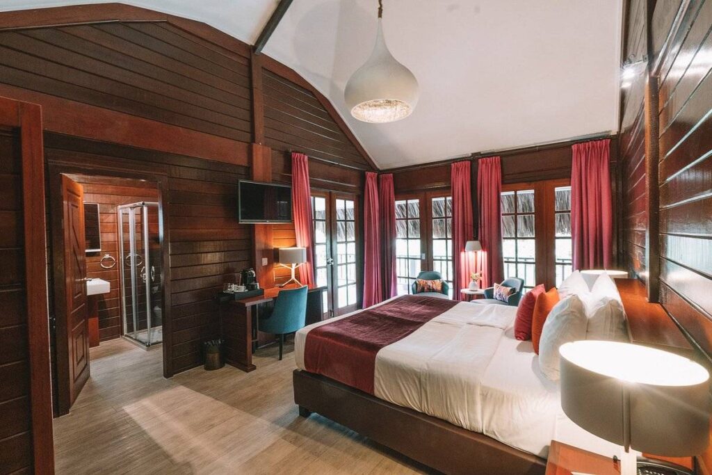 resort room with bed and wood panel walls