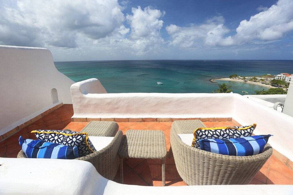 two lounge beds with blue pillows on patio at the ocean