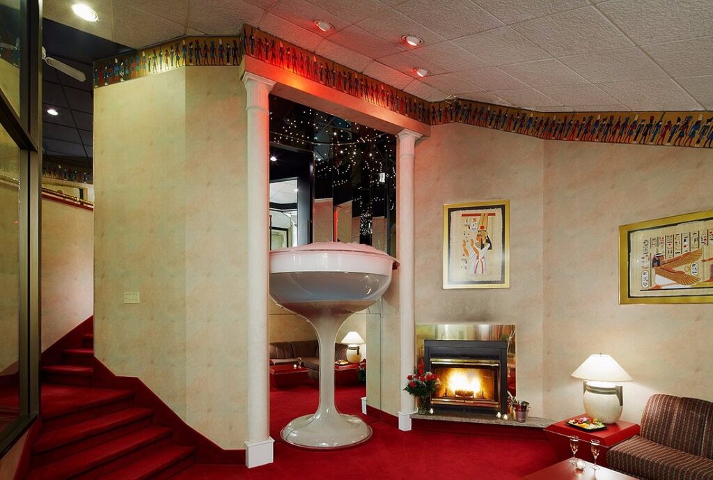 resort room with red carpet and tall champagne shaped tub 