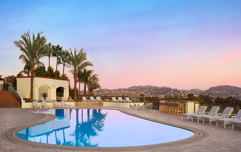 small resort pool with palm trees and mountains in background