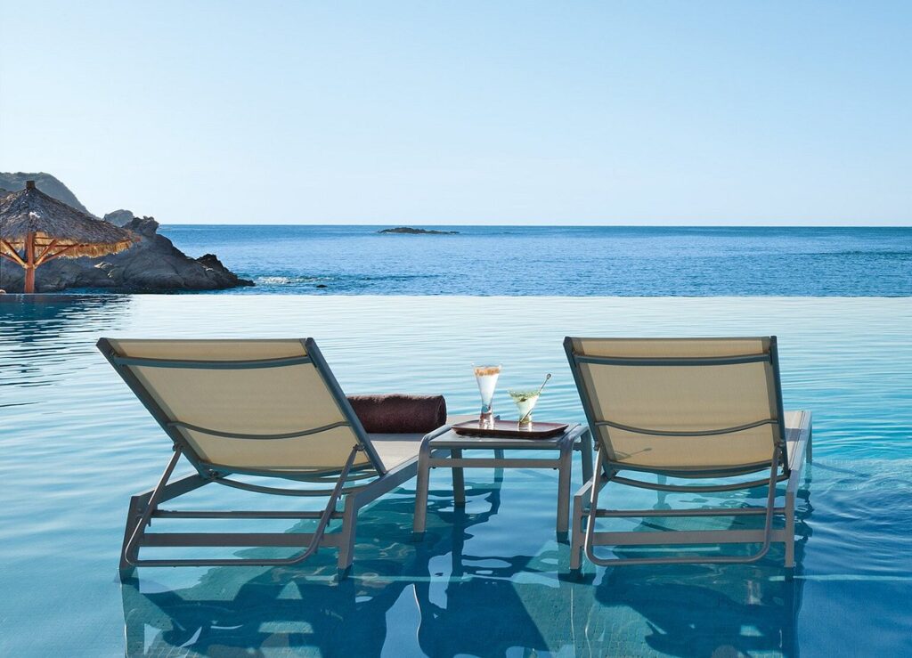 two lounge chairs in infinity pool looking out on the ocean